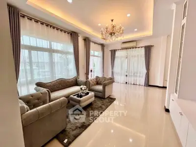 Luxurious living room with elegant chandelier and plush sofas in a bright, spacious setting.