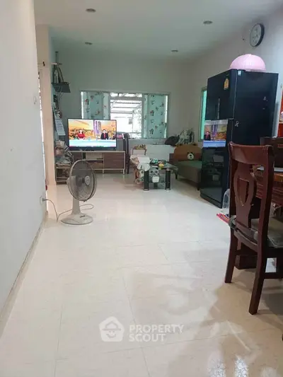 Cozy living room with TV, fan, and dining area in a bright home interior.