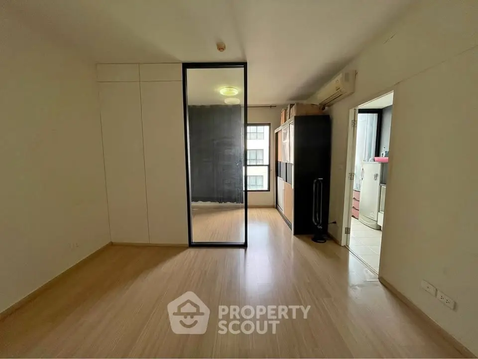 Spacious modern living room with sleek wooden flooring and large window for natural light.