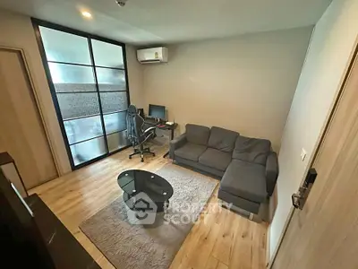 Modern living room with sleek furniture and workspace, featuring a cozy sofa and stylish glass coffee table.