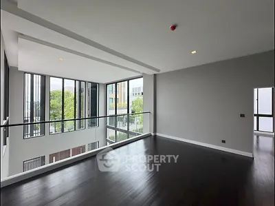 Spacious modern living room with large windows and dark wood flooring.