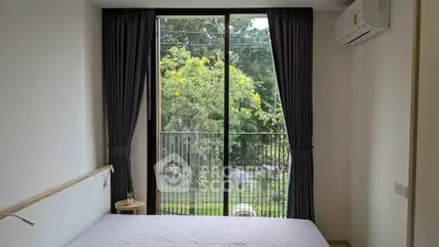Cozy bedroom with large window and garden view, featuring modern air conditioning and minimalist decor.