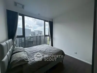 Modern bedroom with large window offering city view in high-rise apartment