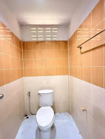 Compact bathroom with tiled walls and modern toilet in a cozy real estate property.