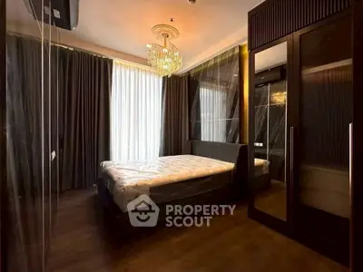 Luxurious bedroom with elegant chandelier and floor-to-ceiling windows in modern apartment.