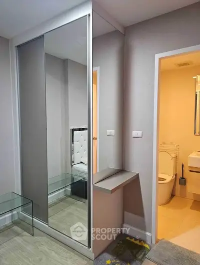 Modern bedroom with mirrored wardrobe and ensuite bathroom in stylish apartment.