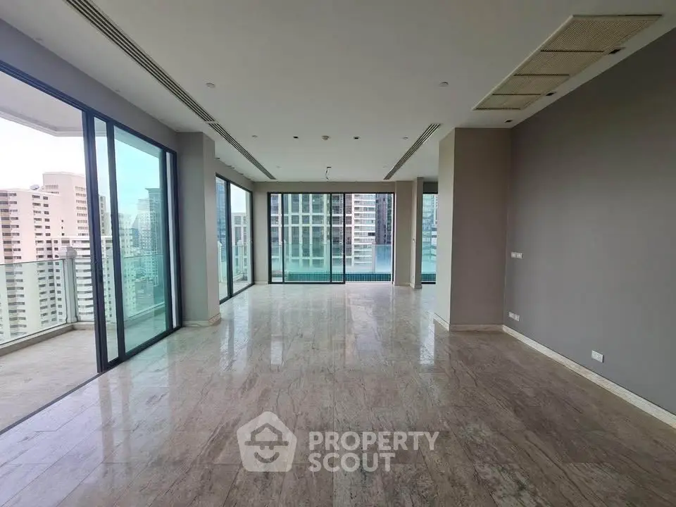 Spacious modern living room with panoramic city views and large balcony access.