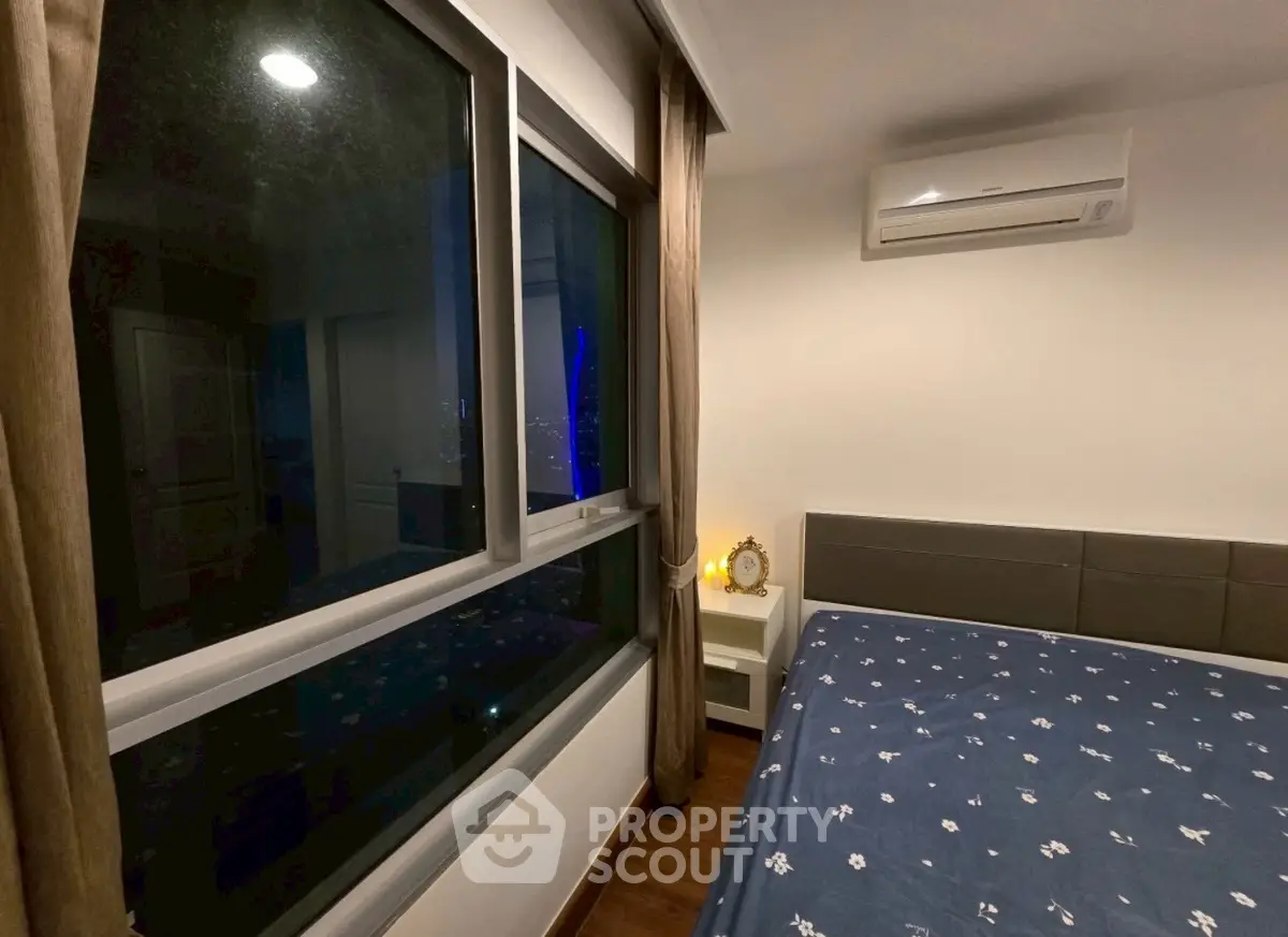 Cozy bedroom with large window and air conditioning unit, perfect for relaxation.