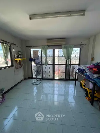 Spacious room with large windows and natural light, ideal for versatile living or office space.