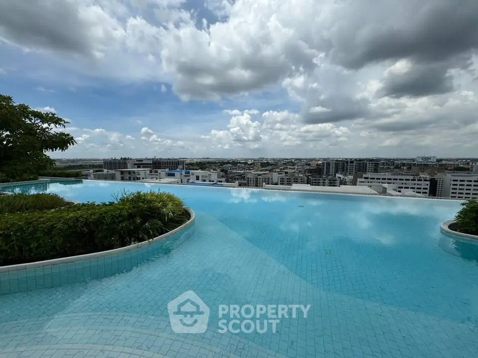 Stunning rooftop infinity pool with panoramic city views under a cloudy sky.