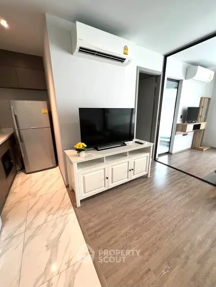Modern living room with sleek flooring, air conditioning, and stylish TV setup in a contemporary apartment.