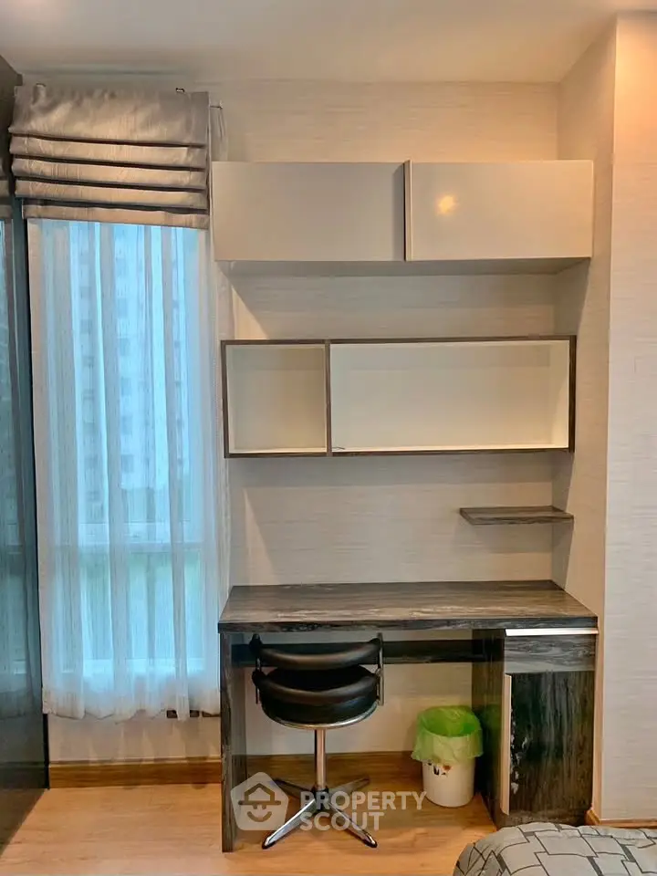 Modern study area with sleek desk and chair, featuring stylish shelving and large window for natural light.