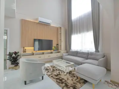 Modern living room with high ceilings, stylish furniture, and large windows for natural light.