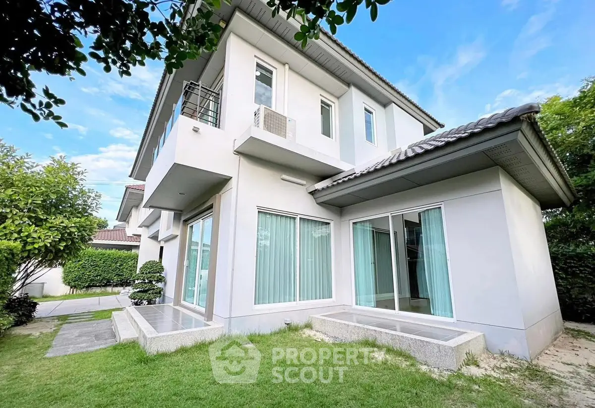 Modern two-story house with large windows and lush green lawn