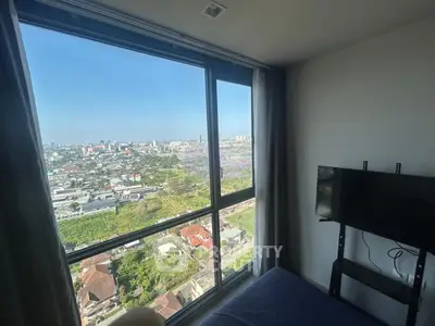 Stunning high-rise bedroom with panoramic city view and mounted TV, perfect for urban living.