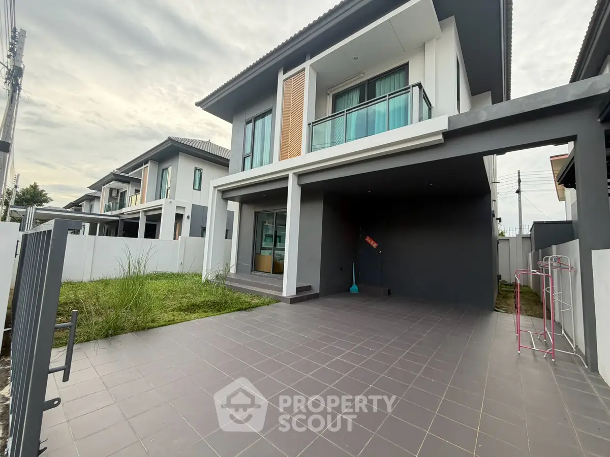 Modern two-story house with spacious driveway and balcony in a suburban neighborhood.