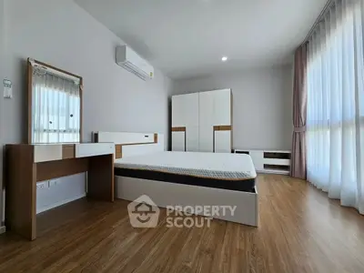 Spacious modern bedroom with wooden flooring and ample natural light