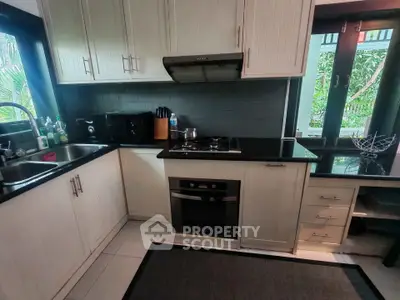 Charming kitchen with modern appliances and garden view, featuring sleek cabinetry and gas stove.