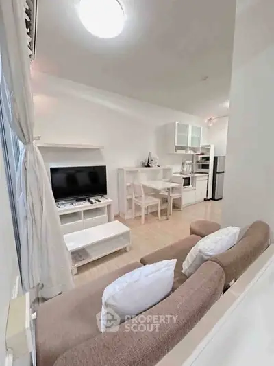 Cozy open-layout living room with modern kitchen and dining area, featuring neutral tones and natural light.