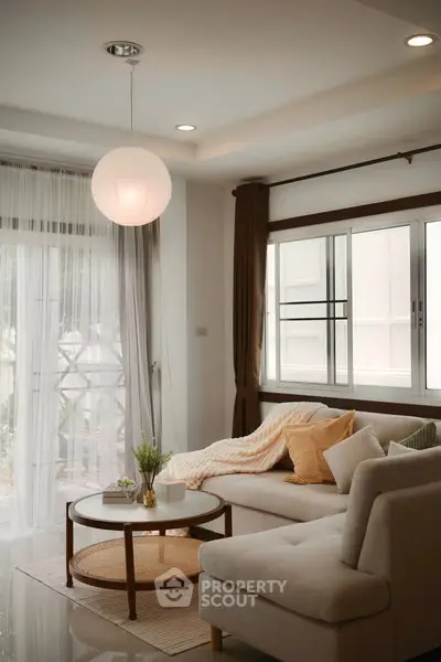 Elegant living room with cozy sofa and modern decor, featuring large windows and soft lighting.