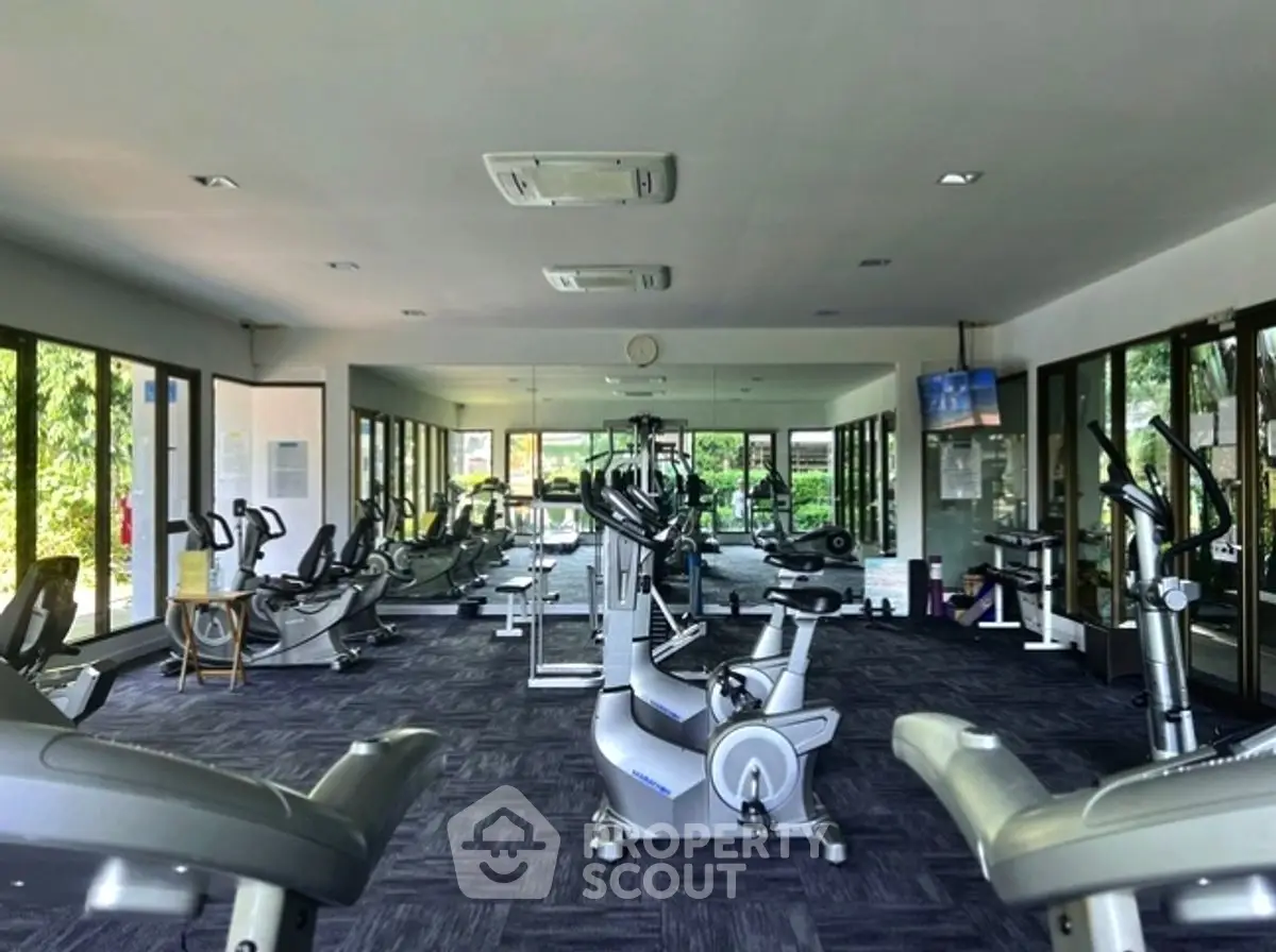 Spacious gym with modern equipment and large windows in luxury real estate property.
