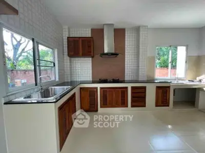Spacious kitchen with modern design, featuring wooden cabinets and large windows for natural light.