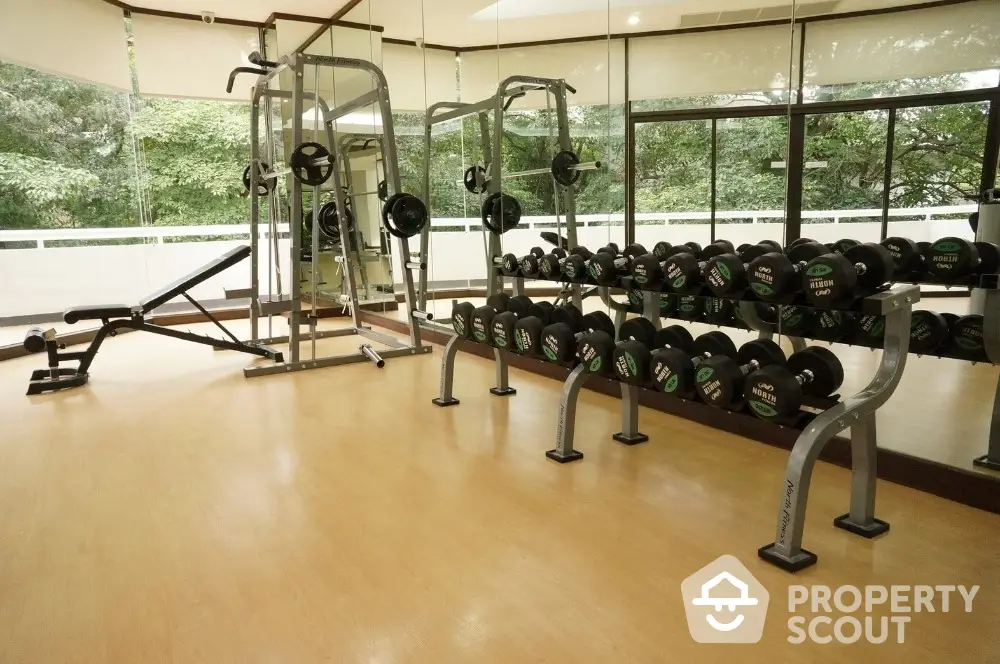 Spacious gym with modern equipment and large windows offering scenic views.