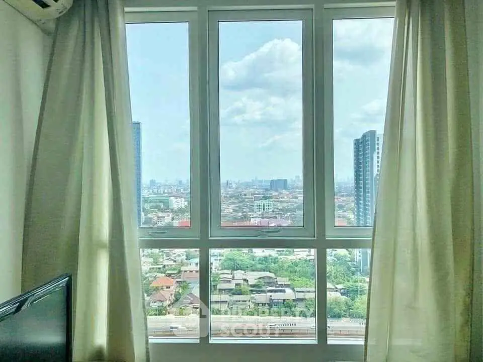 Stunning cityscape view from a high-rise apartment window with natural light and modern curtains.