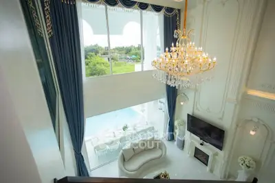 Luxurious living room with high ceilings, elegant chandelier, and large windows offering scenic views.