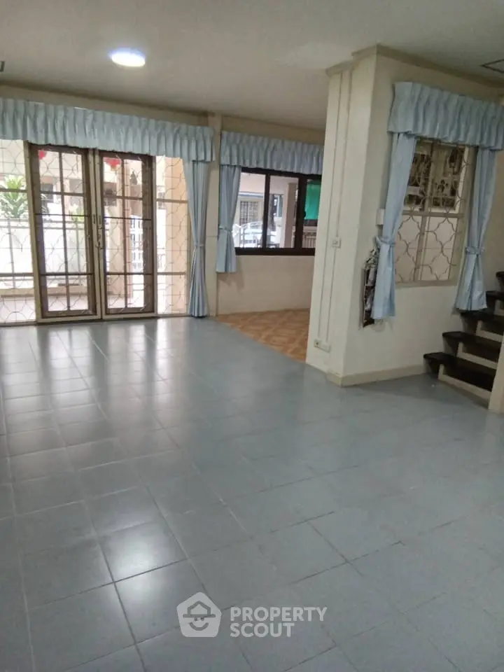 Spacious living room with tiled floor and large windows, perfect for family gatherings.