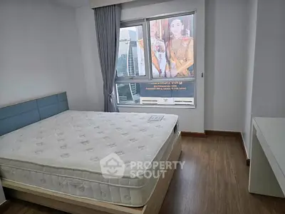 Cozy bedroom with large window and modern furnishings in a stylish apartment.