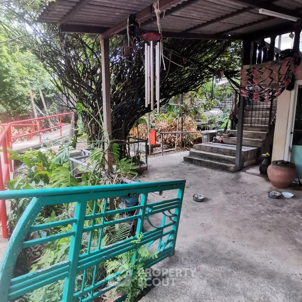 Charming outdoor patio with lush greenery and rustic decor, perfect for relaxation and entertaining.