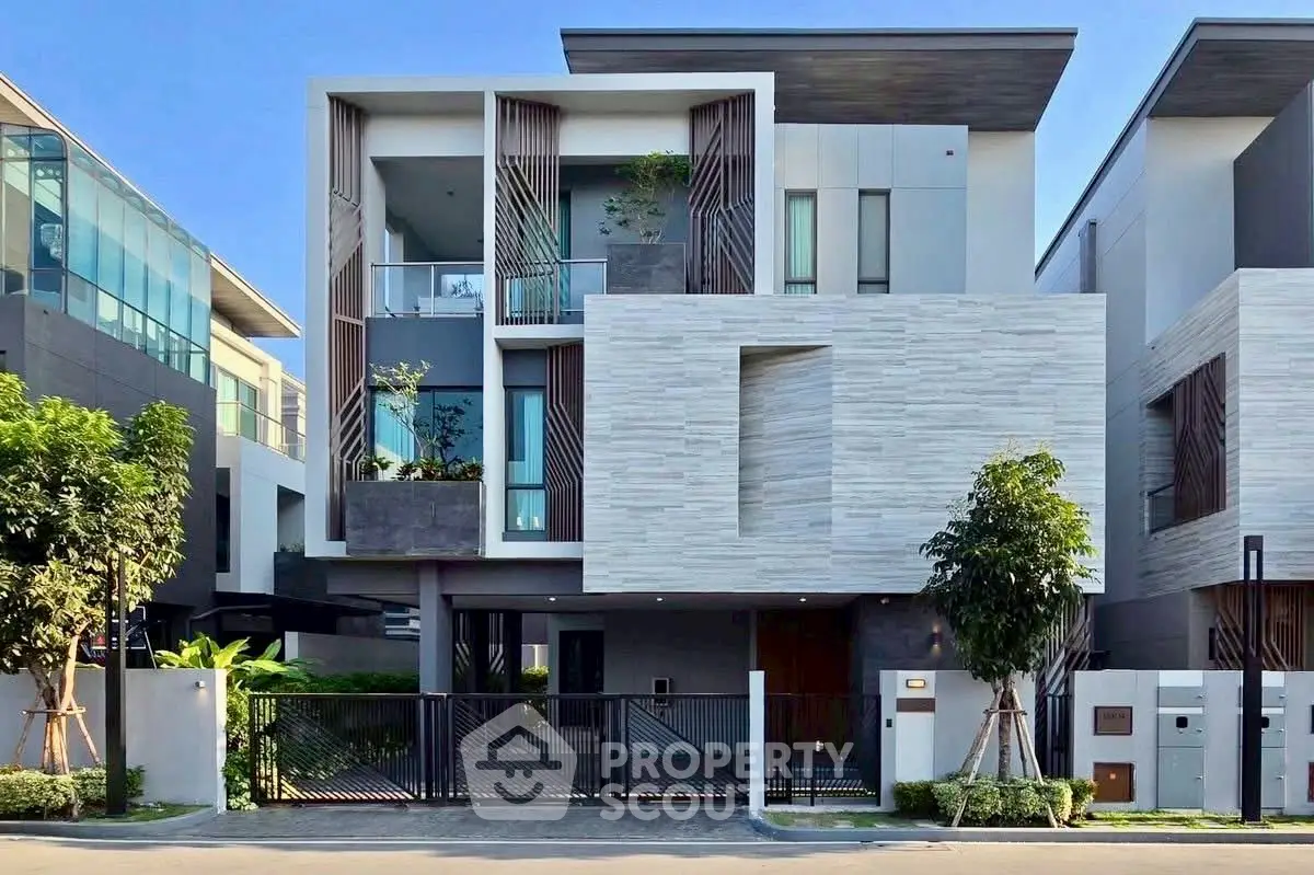 Modern three-story house with sleek design and spacious balcony in a contemporary neighborhood.