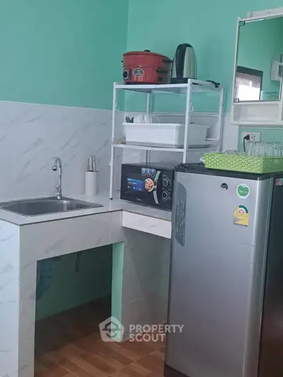 Compact kitchen with modern appliances and sleek design, featuring a microwave and stainless steel fridge.