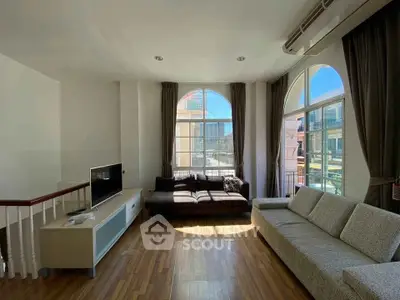 Spacious living room with large windows and modern furniture, offering a bright and inviting atmosphere.