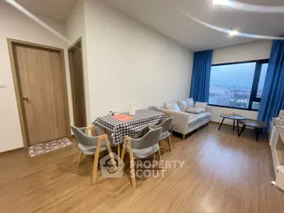 Modern living room with dining area and city view, featuring stylish furniture and wooden flooring.