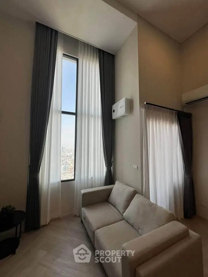 Elegant living room with high ceilings and large windows offering stunning city views.