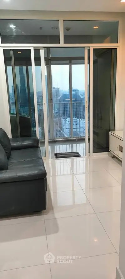 Modern living room with sleek sofa and stunning city view from large glass doors.
