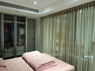 Modern bedroom with large windows and elegant curtains, featuring a cozy bed and sleek wardrobe.