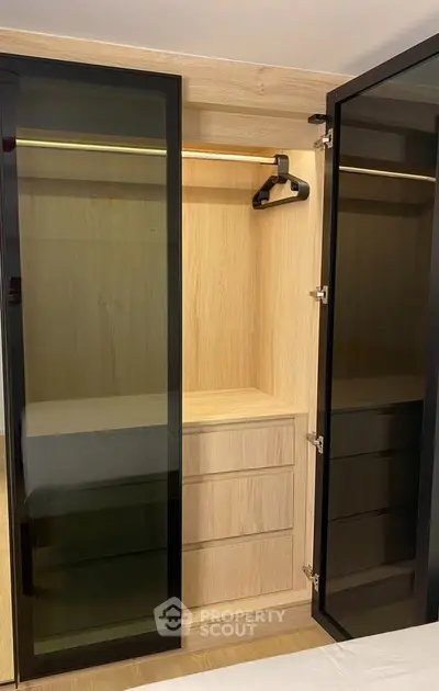 Modern wooden wardrobe with glass doors and built-in drawers in a stylish bedroom.