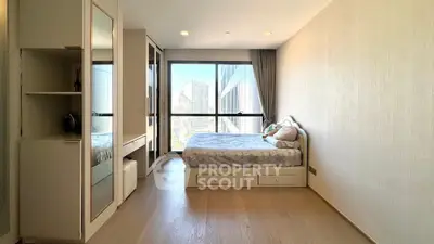 Modern bedroom with large window and city view, featuring sleek furniture and wooden flooring.