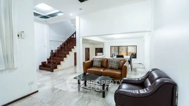 Spacious living room with elegant staircase and modern furniture in a stylish home.
