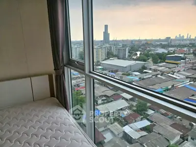 High-rise apartment bedroom with panoramic city view through large windows.