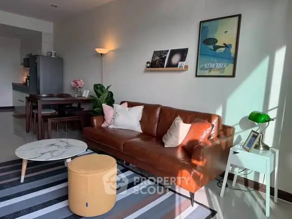 Stylish living room with leather sofa, modern decor, and natural light in a cozy apartment.