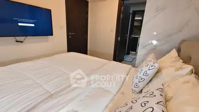 Cozy bedroom with modern decor and wall-mounted TV, perfect for relaxation.