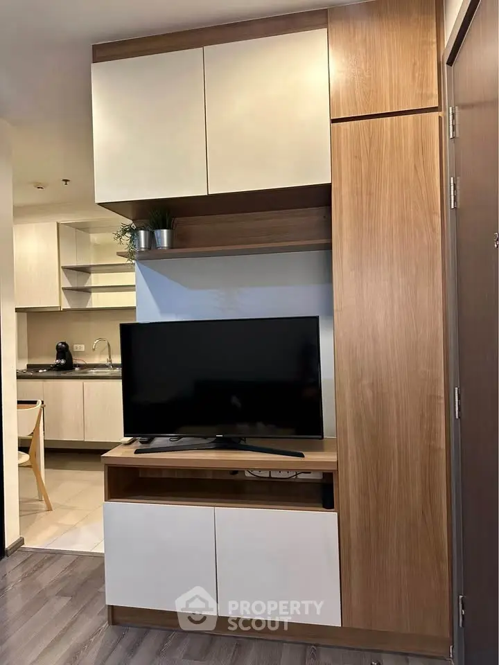 Modern living room with sleek TV unit and stylish kitchen in background
