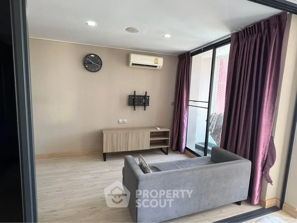 Modern living room with sleek design and balcony access, featuring a cozy sofa and wall-mounted air conditioning.