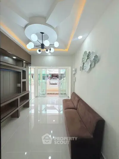 Modern living room with stylish ceiling lights and sleek brown sofa, featuring large windows for natural light.