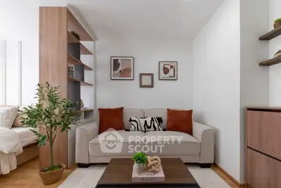 Modern living room with stylish decor and cozy seating area, featuring elegant shelving and artwork.