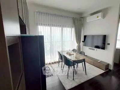 Modern dining area with sleek furniture and large window offering natural light and city views.